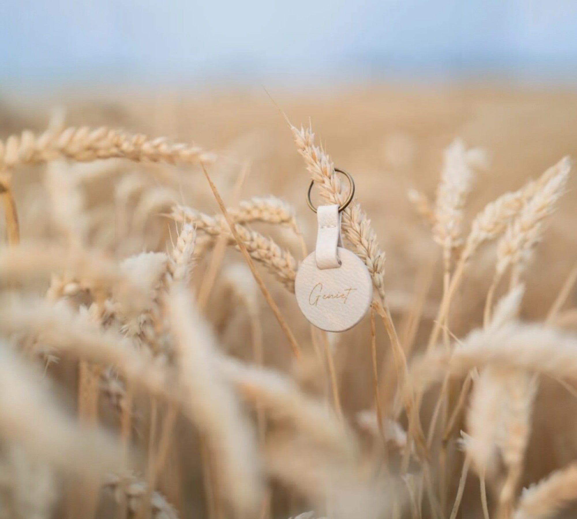 Zusss sleutelhanger in beige met de tekst ‘geniet’, stijlvolle accessoire verkrijgbaar bij cadeauwinkel Omdat in Uden, passend bij portemonnees en pasjeshouders.