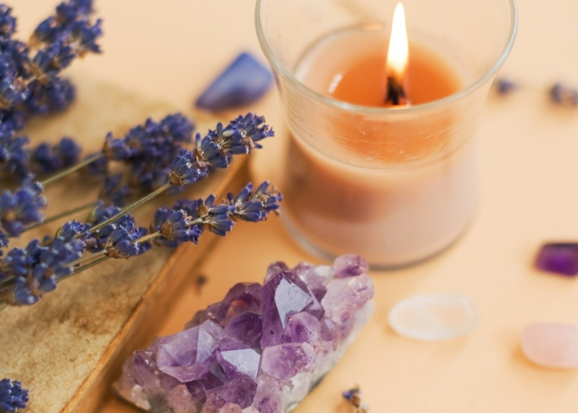Brandende geurkaars met amethist en andere edelstenen, gecombineerd met lavendel voor een rustgevende en symbolische sfeer, verkrijgbaar bij cadeauwinkel Omdat in Uden.
